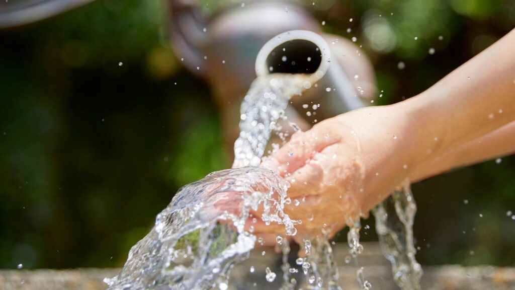 Water flowing from a pipe onto a person's hand