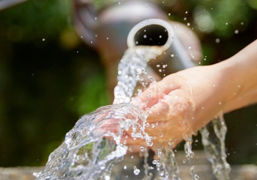 Water flowing from a pipe onto a person's hand